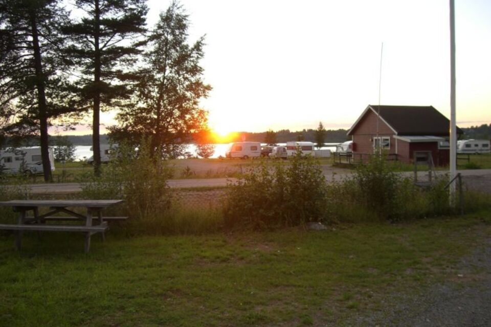 Töre Camping där man ser vattnet och en solnedgång med vissa husvagnar och husbilar.